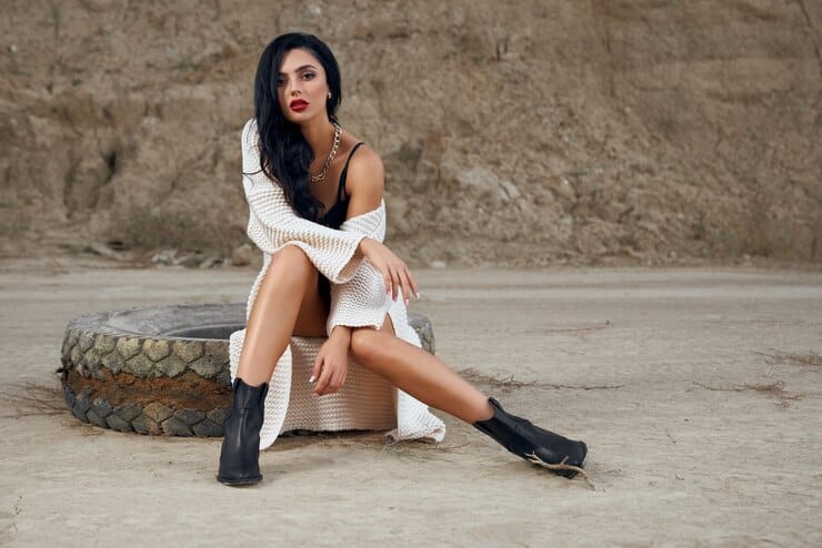 sensual-young-brunette-black-bodywear-knitted-cardigan-sitting-old-big-tyre-desert_7502-7884